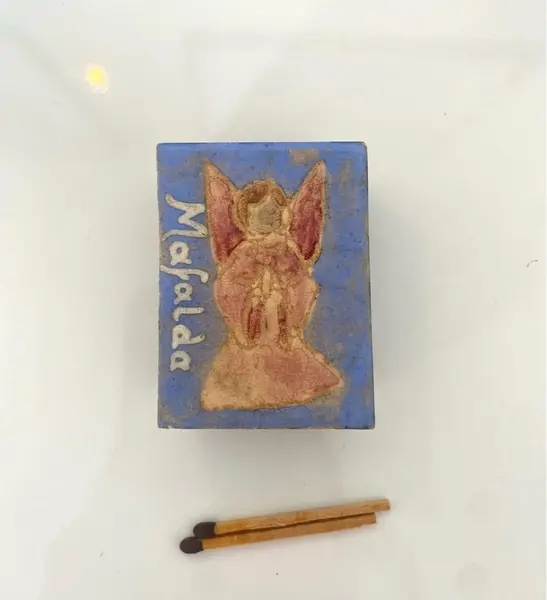 Foto de um(a) Caixa de fósforo e porcelana, da categoria de Outros colecionáveis. Caixa de fósforos com placa de porcelana com pintura de anjo. De uma extinta loja de bolsas de São Paulo, chamada “Mafalda”. Mostrado de uma perspectiva diferente. Vendido no marketplace Trésors.