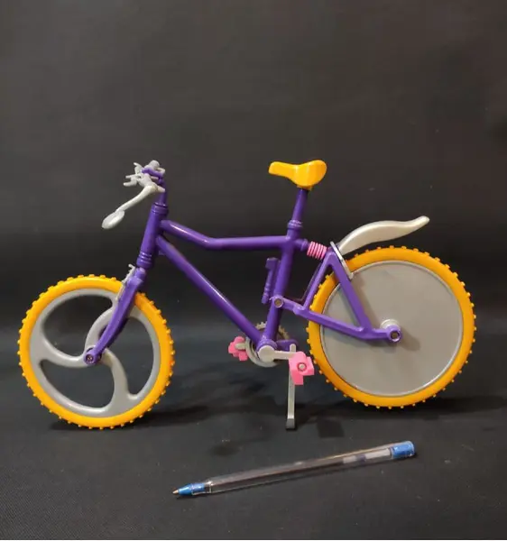 Foto de um(a) Mini Bicicleta Barbie Anos 90, da categoria de Móveis e miniaturas para bonecas. Miniatura de bicicleta em plástico com pneus em borracha amarela com garradeiras. Sem marca do fabricante, década de 1990,... Mostrado de uma perspectiva diferente. Vendido no marketplace Trésors.