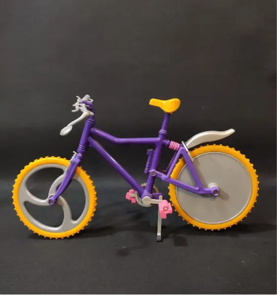 Foto de um(a) Mini Bicicleta Barbie Anos 90, da categoria de Móveis e miniaturas para bonecas. Miniatura de bicicleta em plástico com pneus em borracha amarela com garradeiras. Sem marca do fabricante, década de 1990,... Mostrado de uma perspectiva diferente. Vendido no marketplace Trésors.