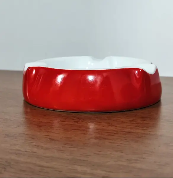 Foto de um(a) Cinzeiro Porcelana Steatita, Década de 1960, da categoria de Cinzeiros e coletores. Cinzeiro de mesa em porcelana branca com moldura em vermelho e o logo do clube 12 de agosto, fundado em 12 de agosto de 1872... Mostrado de uma perspectiva diferente. Vendido no marketplace Trésors.