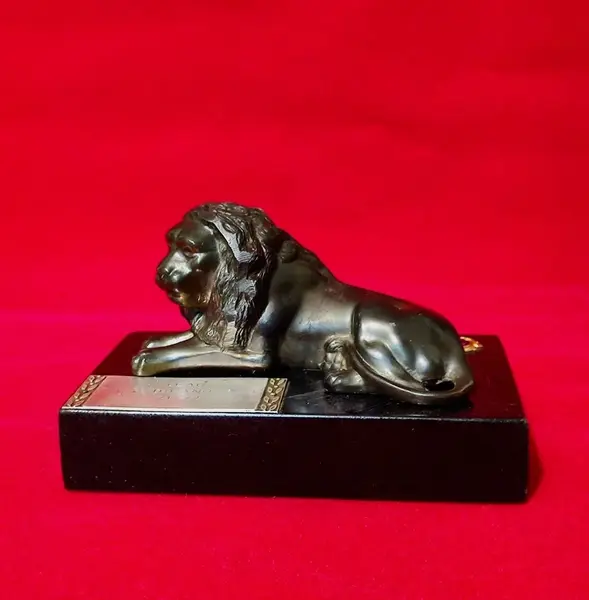 Foto de um(a) Troféu Leão do Ano, 71/72, da categoria de Escultura. Troféu Lions 1971/1972 - Leão do Ano. Em bronze com base de granito preto. A: 7 cm / L: 12 cm / P: 7,4 cm peso: 738 g. Mostrado de uma perspectiva diferente. Vendido no marketplace Trésors.