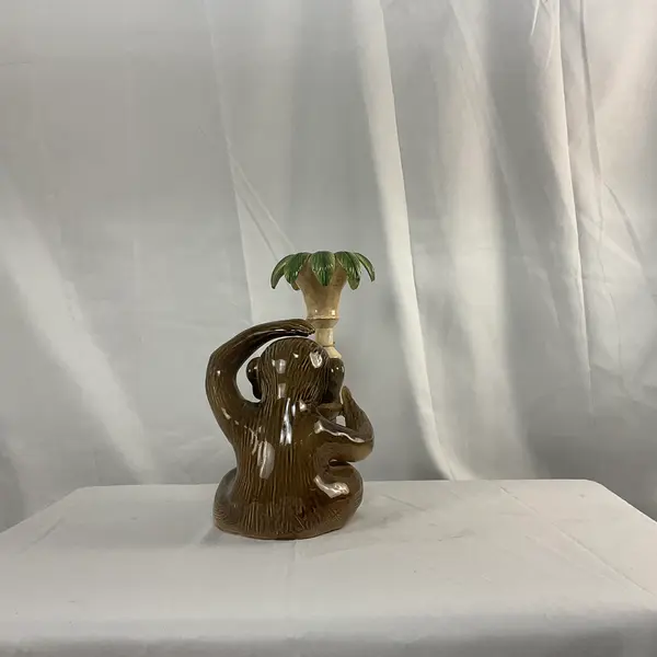 Foto de um(a) Castiçal em Cerâmica em Forma de Macaco, da categoria de Castiçais. Castiçal fabricado em cerâmica, representando um macaco junto a um pilar com folhas. Mostrado de uma perspectiva diferente. Vendido no marketplace Trésors.