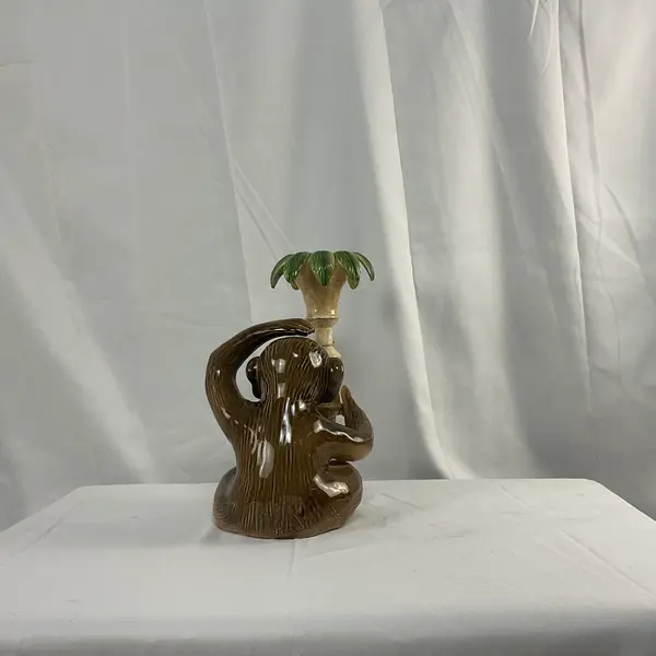 Foto de um(a) Castiçal em Cerâmica em Forma de Macaco, da categoria de Castiçais. Castiçal fabricado em cerâmica, representando um macaco junto a um pilar com folhas. Mostrado de uma perspectiva diferente. Vendido no marketplace Trésors.