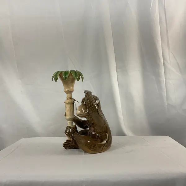 Foto de um(a) Castiçal em Cerâmica em Forma de Macaco, da categoria de Castiçais. Castiçal fabricado em cerâmica, representando um macaco junto a um pilar com folhas. Mostrado de uma perspectiva diferente. Vendido no marketplace Trésors.