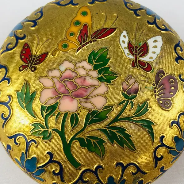 Foto de um(a) Porta-jóia em metal dourado, da categoria de Porta-Jóias. Porta-jóia em metal dourado com figura de borboletas e flor em policromia, interior na cor azul. Mede 4cm altura x 7cm... Mostrado de uma perspectiva diferente. Vendido no marketplace Trésors.