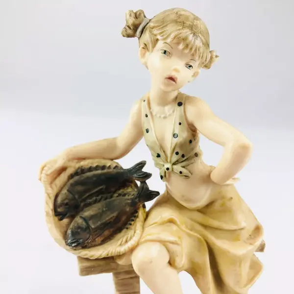 Foto de um(a) Escultura de menina com cesta de peixes, da categoria de Escultura. Escultura de menina com cesta de peixes sentada em um banco, mede 15cm altura. Mínimas marcas de uso. Em bom estado de... Mostrado de uma perspectiva diferente. Vendido no marketplace Trésors.