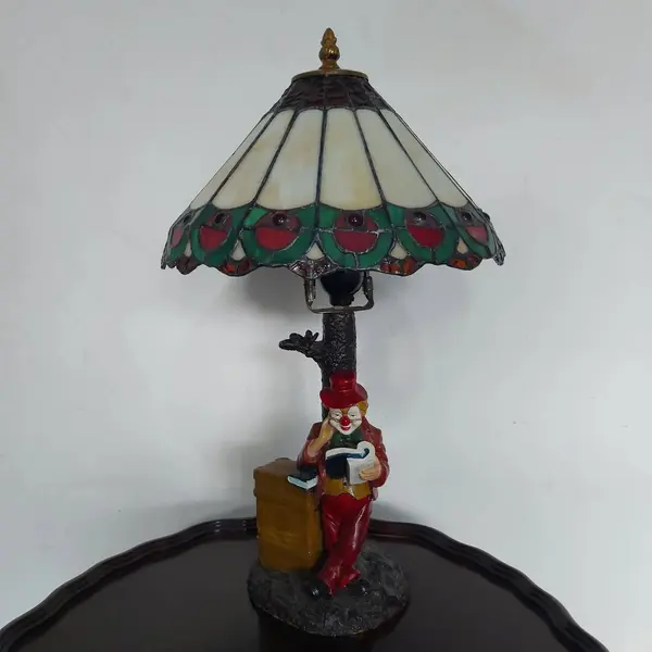 Foto de um(a) Abajur estilo Tiffany com escultura de palhaço, da categoria de Abajures. Bellisimo abajur estilo Tiffany com escultura de palhaço lendo livro. Medidas: altura 48 cm x diâmetro cúpula 28 cm x base... Mostrado de uma perspectiva diferente. Vendido no marketplace Trésors.