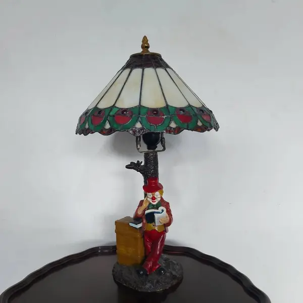 Foto de um(a) Abajur estilo Tiffany com escultura de palhaço, da categoria de Abajures. Bellisimo abajur estilo Tiffany com escultura de palhaço lendo livro. Medidas: altura 48 cm x diâmetro cúpula 28 cm x base... Mostrado de uma perspectiva diferente. Vendido no marketplace Trésors.