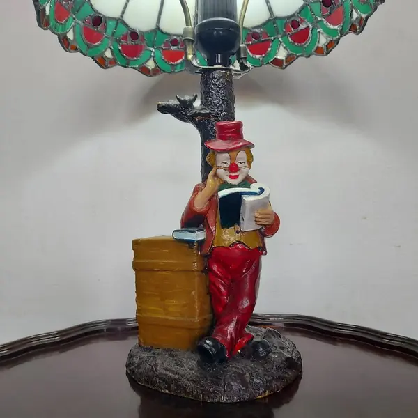 Foto de um(a) Abajur estilo Tiffany com escultura de palhaço, da categoria de Abajures. Bellisimo abajur estilo Tiffany com escultura de palhaço lendo livro. Medidas: altura 48 cm x diâmetro cúpula 28 cm x base... Mostrado de uma perspectiva diferente. Vendido no marketplace Trésors.