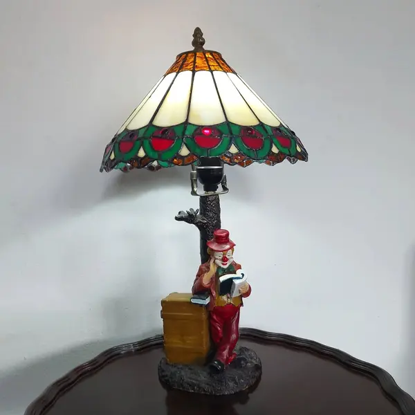 Foto de um(a) Abajur estilo Tiffany com escultura de palhaço, da categoria de Abajures. Bellisimo abajur estilo Tiffany com escultura de palhaço lendo livro. Medidas: altura 48 cm x diâmetro cúpula 28 cm x base... Mostrado de uma perspectiva diferente. Vendido no marketplace Trésors.