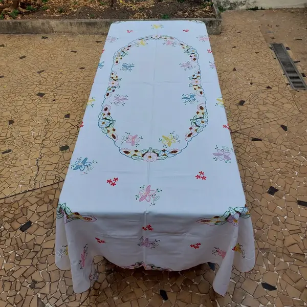 Foto de um(a) Toalha de mesa bordada, da categoria de Toalhas de Mesa. Belissima e grandiosa toalha de mesa bordada com flores coloridas. Medidas: comprimento 285 cm x largura 150 cm. Mostrado de uma perspectiva diferente. Vendido no marketplace Trésors.