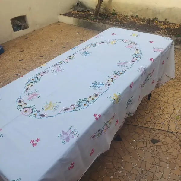 Foto de um(a) Toalha de mesa bordada, da categoria de Toalhas de Mesa. Belissima e grandiosa toalha de mesa bordada com flores coloridas. Medidas: comprimento 285 cm x largura 150 cm. Mostrado de uma perspectiva diferente. Vendido no marketplace Trésors.