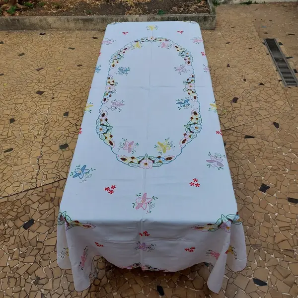 Foto de um(a) Toalha de mesa bordada, da categoria de Toalhas de Mesa. Belissima e grandiosa toalha de mesa bordada com flores coloridas. Medidas: comprimento 285 cm x largura 150 cm. Mostrado de uma perspectiva diferente. Vendido no marketplace Trésors.