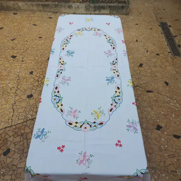 Foto de um(a) Toalha de mesa bordada, da categoria de Toalhas de Mesa. Belissima e grandiosa toalha de mesa bordada com flores coloridas. Medidas: comprimento 285 cm x largura 150 cm. Mostrado de uma perspectiva diferente. Vendido no marketplace Trésors.