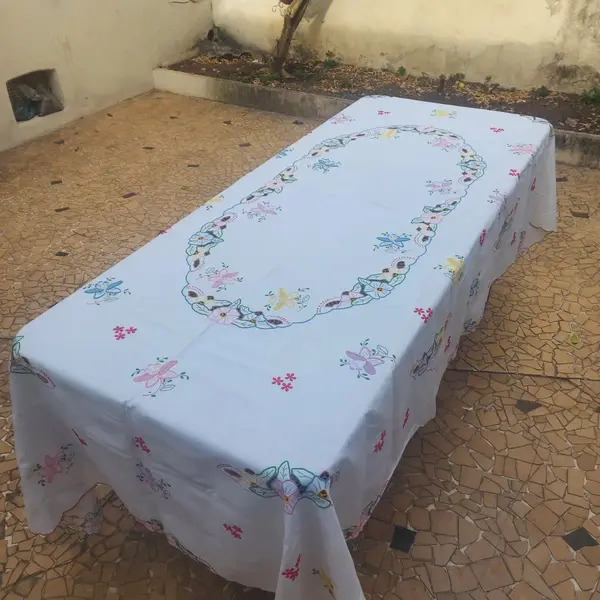Foto de um(a) Toalha de mesa bordada, da categoria de Toalhas de Mesa. Belissima e grandiosa toalha de mesa bordada com flores coloridas. Medidas: comprimento 285 cm x largura 150 cm. Mostrado de uma perspectiva diferente. Vendido no marketplace Trésors.