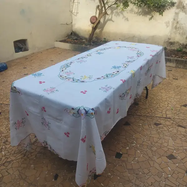 Foto de um(a) Toalha de mesa bordada, da categoria de Toalhas de Mesa. Belissima e grandiosa toalha de mesa bordada com flores coloridas. Medidas: comprimento 285 cm x largura 150 cm. Mostrado de uma perspectiva diferente. Vendido no marketplace Trésors.