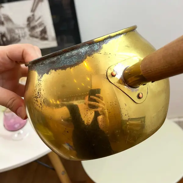 Foto de um(a) ​Panela decorativa em metal, da categoria de Panelas. Panela decorativa em metal amarelo e cabo em madeira. Apresenta charmosas marcas do tempo. Medidas: 32x11x16cm. Mostrado de uma perspectiva diferente. Vendido no marketplace Trésors.