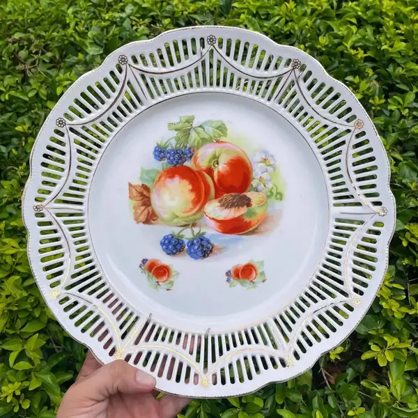 Foto de um(a) Antigo Grande Prato Medalhão Porcelana Alemã Fenestrado, da categoria de Pratos Decorativos. Schumann, Bavaria. Germany. Antigo e grande prato medalhão decorativo com decoração de frutas, dita natureza morta, borda... Mostrado de uma perspectiva diferente. Vendido no marketplace Trésors.