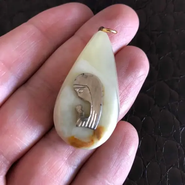 Foto de um(a) Arte Sacra Antigo Pingente Dourado De Santa Em Pedra Ônix, da categoria de Objetos religiosos e espirituais. Peça muito delicada, de meados do século XX. Medida 4cm. Mostrado de uma perspectiva diferente. Vendido no marketplace Trésors.