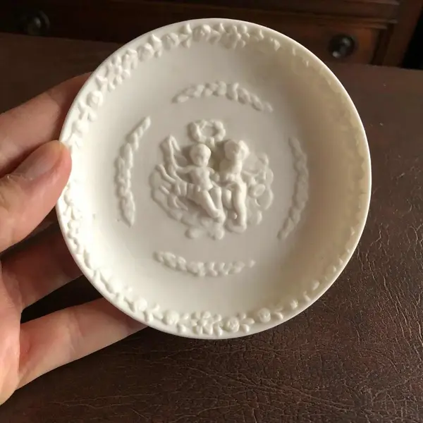 Foto de um(a) Antigo Pratinho De Parede Em Biscuit Francês, da categoria de Pratos Decorativos. Antigo pratinho de parede em biscuit francês ricamente decorado com querubins e flores. Em perfeito estado. Mede: 11cm. Mostrado de uma perspectiva diferente. Vendido no marketplace Trésors.