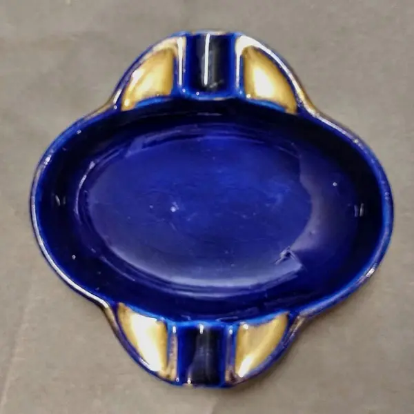 Foto de um(a) Cinzeiro em Porcelana Azul Cobalto com Filete Dourado, Década de 1940, da categoria de Cinzeiros e coletores. Cinzeiro em porcelana azul cobalto com filete dourado, década de 1940. A: 3 cm / L: 14,5 cm Peso: 300 g. Mostrado de uma perspectiva diferente. Vendido no marketplace Trésors.