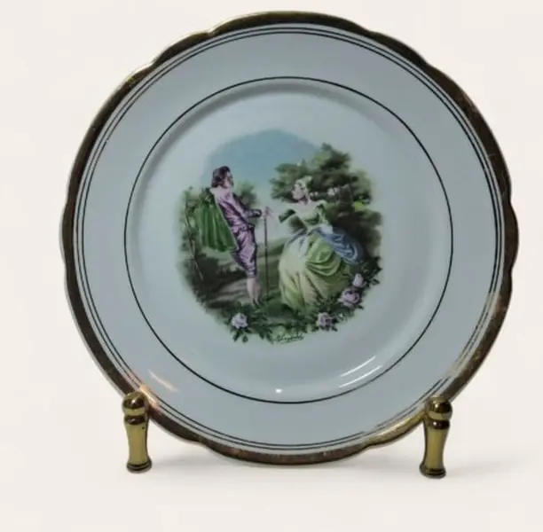 Foto de um(a) Prato decorativo em porcelana Real, da categoria de Pratos Decorativos. Prato com bordas douradas e centro com cena galante. Lindo e em ótimo estado. Porcelana Real. Acompanha suporte regulável em... Mostrado de uma perspectiva diferente. Vendido no marketplace Trésors.