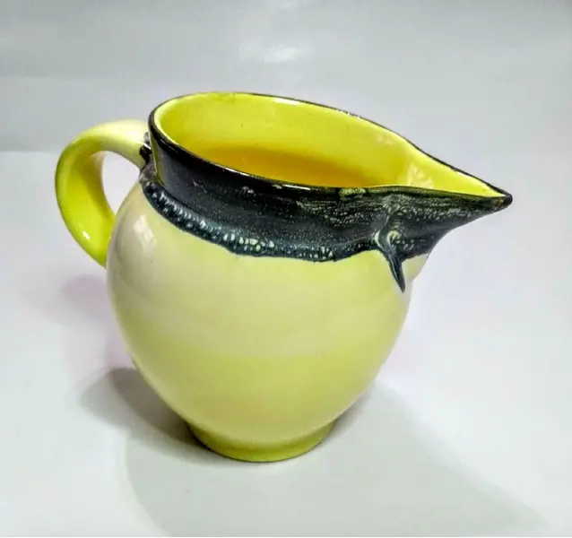 Foto de um(a) Cremeira Amarelinha Anos 70, da categoria de Cremeiras. Cremeira em porcelana amarela e cinza, década de 1970.A: 12cm / Diâmetro: 6cm peso: 354g. Mostrado de uma perspectiva diferente. Vendido no marketplace Trésors.