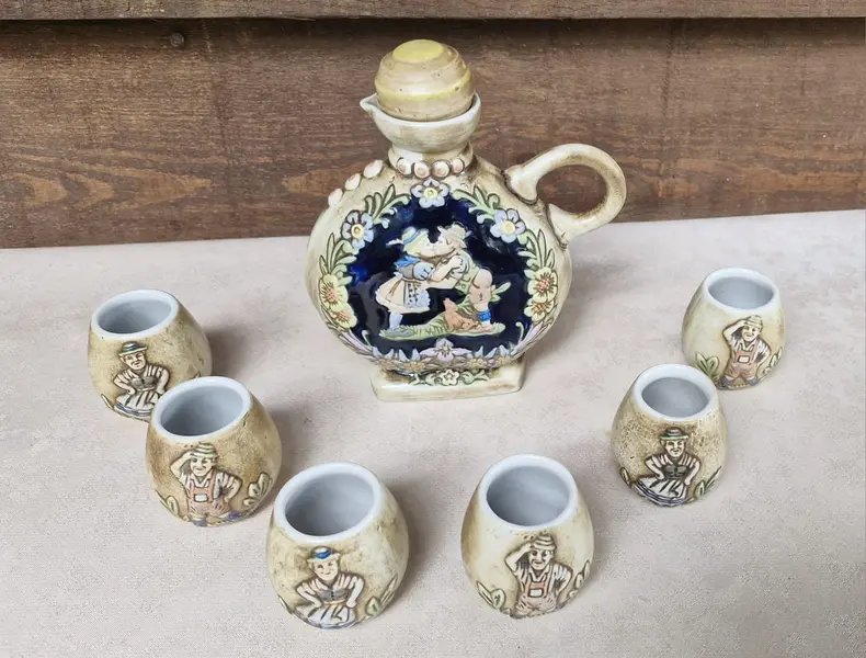 Foto de um(a) Antiga licoreira com 6 copinhos - Peça de coleção, da categoria de Conjuntos de servir. Raro e antigo conjunto de licoreira com 6 copinhos da marca Ceramarte, com trabalho em relevo em policromia, representando... Mostrado de uma perspectiva diferente. Vendido no marketplace Trésors.