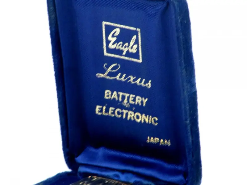 Foto de um(a) Antigo isqueiro EAGLE/ LUXUS, da categoria de Isqueiros e isqueiros. Antigo isqueiro em metal dourado da manufatura EAGLE/ LUXUS BATTERY ELECTRONIC JAPAN.No estojo original em veludo azul.... Mostrado de uma perspectiva diferente. Vendido no marketplace Trésors.